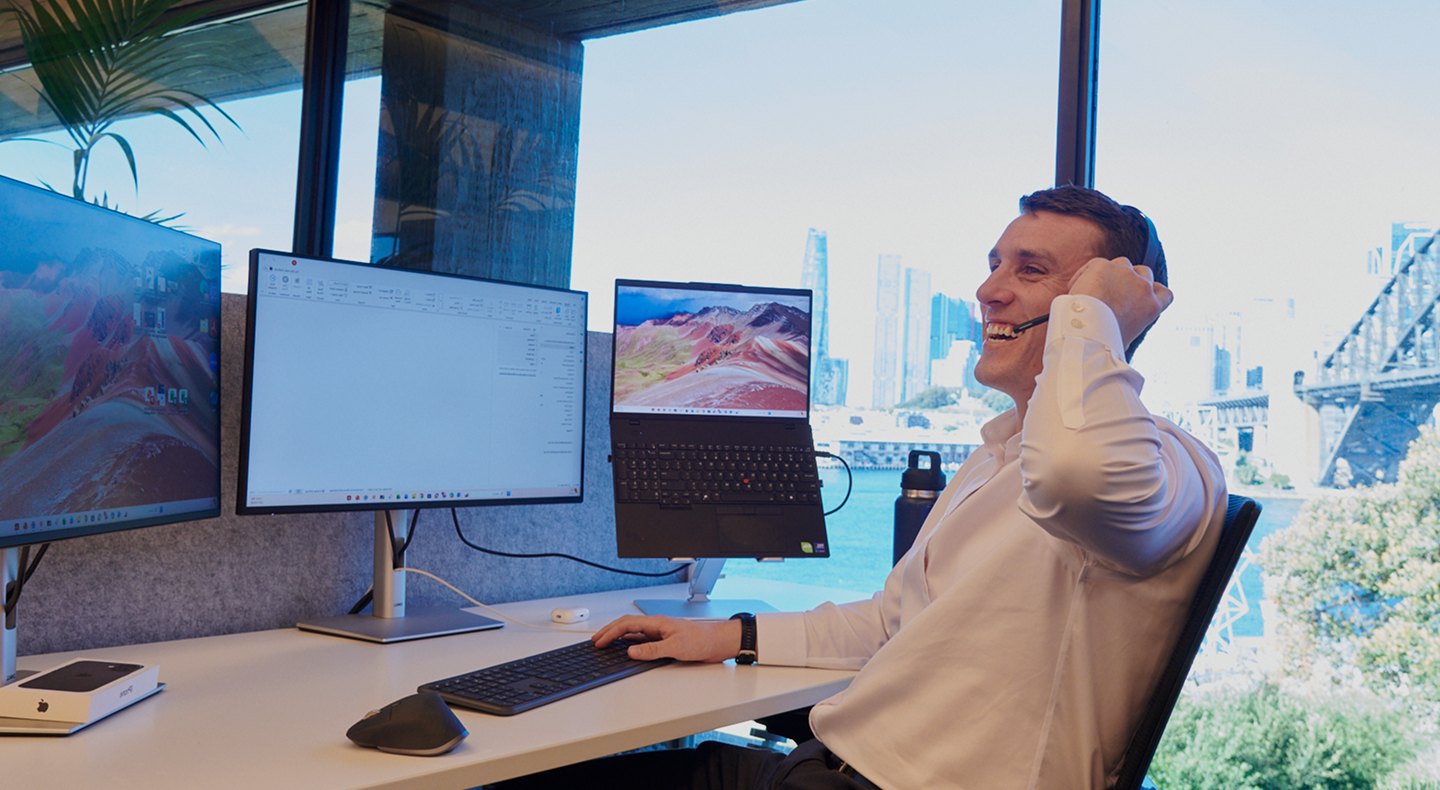 SHC team member on a headset call at a desk overlooking Sydney Harbour